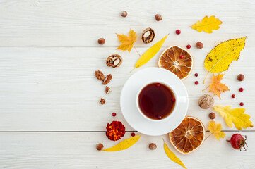 Autumn layout with tea and dried oranges on a white wooden background. Copy space.