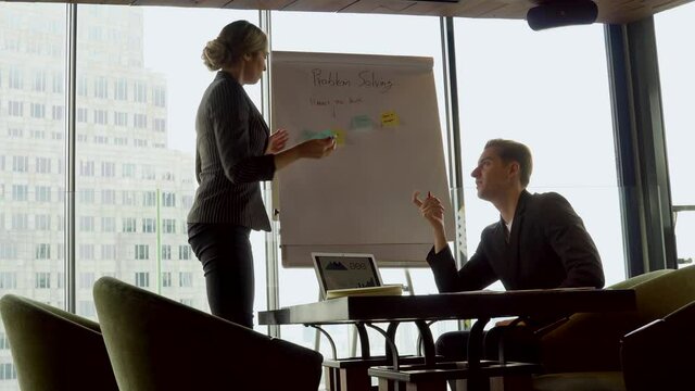 Young businessmen and business women sitting in meeting room discussing with information data with  post it notes and flipchart near skyscraper office window . entrepreneur talking strategy problem
