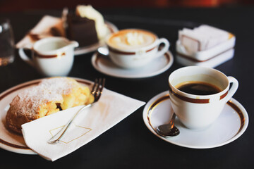 Coffee with cream in cap and with chocolate cake on table in cafe