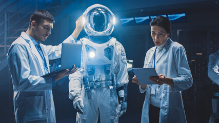 Diverse Team of Aerospace Scientists and Engineers Wearing White Coats have Discussion, Use...