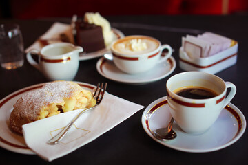 Coffee with cream in cap and with chocolate cake on table in cafe