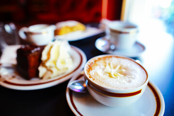 Coffee with cream in cap and with chocolate cake on table in cafe