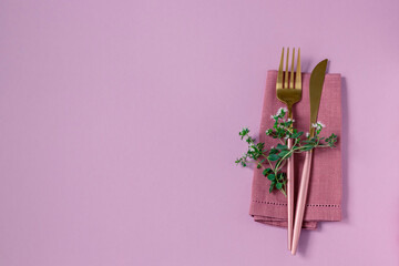 Knife and fork and linen napkin on pink background. Holiday celebration.