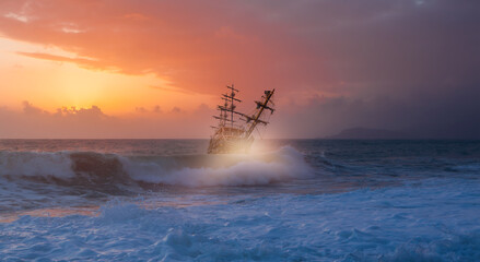 Sailing old ship in storm sea against dramatic sunset