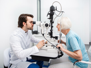 Fototapeta na wymiar Optometrist doing sight testing for a senior woman at modern clinic. Eye exam and vision diagnostic