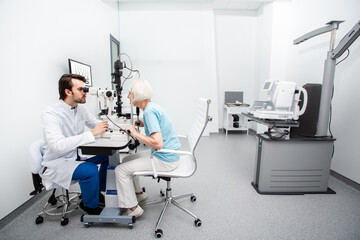 Optometrist and senior patient while vision diagnostic at a modern clinic. Eye exam and vision...