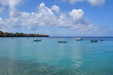 Fototapeta na wymiar Cloudy sky and fishing boats in the turquoise water at Playa Grandi at Westpunt Curacao