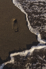 Footprints in the sand and sea waves