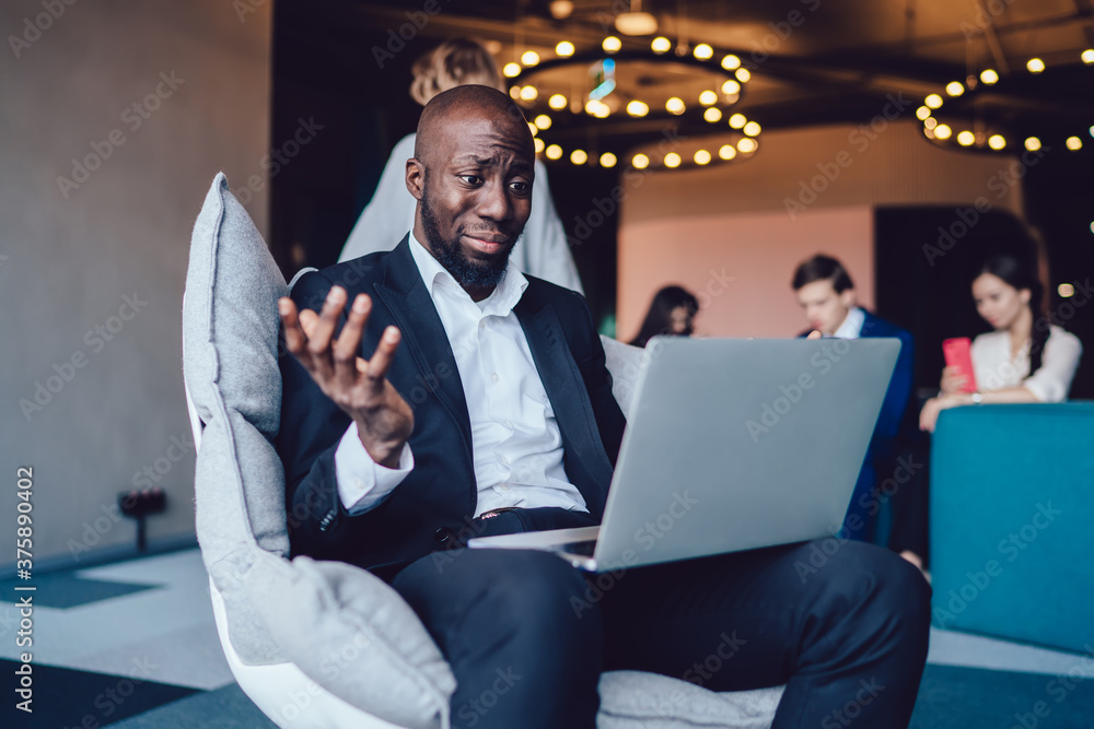 Poster dark skinned male employer watching tutorial webinar via laptop application using 4g internet confus