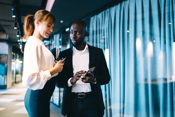 Diverse colleagues sharing media information via mobile gadgets using bluetooth connection in...