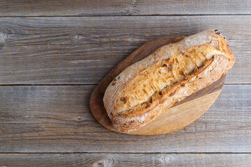 Freshly baked organic ciabatta lies on a cutting board on a wooden table. Traditional Italian bread. Homemade pastries. Place for text