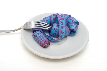 Diet and weight loss concept. Blue measuring tape in white plate wound on fork on white background