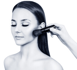 Obraz premium Beautiful woman with closed eyes and female hand applying make-up on her face. Isolated on white.