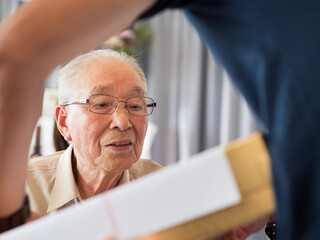 An elderly man looking at something he is receiving with great interest