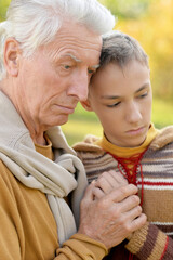 Fototapeta premium Close up portrait of sad grandfather and grandson hugging