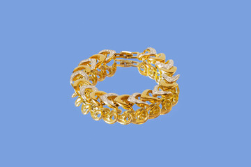 Gold bracelet with white platinum and small diamonds on mirror surface on blue background