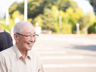 An elderly Asian man smiling happily outside