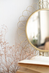 A round old mirror with a delicate frame stands on the table