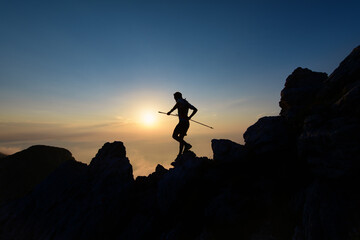 Sky runner in silhouette at sunset among the rocks