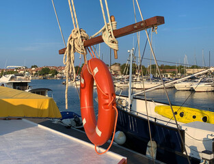 Lifebuoy and rope hanging on a ship, docked in a harbor during the summer