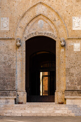 Fototapeta na wymiar Entrance door to the main office of the Banca Monte dei Paschi di Siena, one of the oldest banks in the world. The building is the Palazzo Salimbeni, a Gothic style palace on the Piazza Salimbeni.