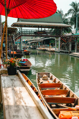 Fototapeta na wymiar A part of the floating market in Thailand, captured emplty boats and a bridge overarching the river