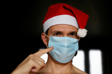 Portrait of man in medical face mask and Santa Claus hat. Christmas celebration during coronavirus pandemic