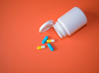 Yellow-white and blue capsules with open white packaging on a brown-orange surface, top view.