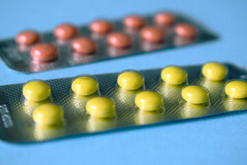 Two packages with pills of yellow and orange on a blue background.