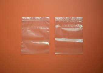 Two small disposable plastic bags with zip fastener on a brown background. View from above.