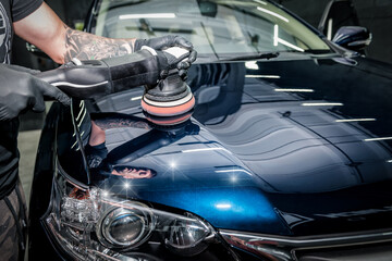 Obraz na płótnie Canvas Man with orbital polisher polishing car.