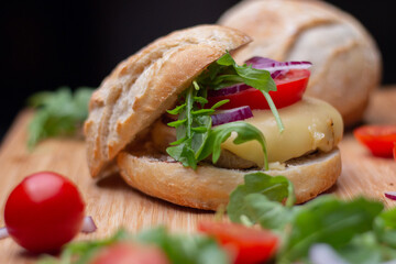 Home made hamburger with beef, onion, tomato, lettuce and cheese. Fresh burger closeup on wooden rustic table with fresh vegetables. Cheeseburger.