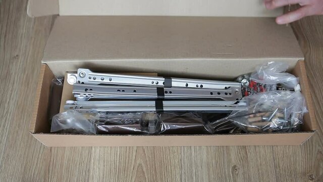A furniture maker opens a box with furniture fittings. Preparation of furniture assembly.
