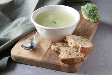 Broccoli soup in white plate over wooden background