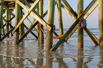 Hammock, sandals, and backpack under a pier at Isle of Palms Beach in South Carolina.