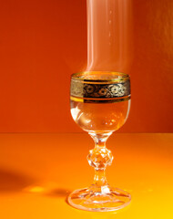 A splash of alcohol in the glass on an orange background.