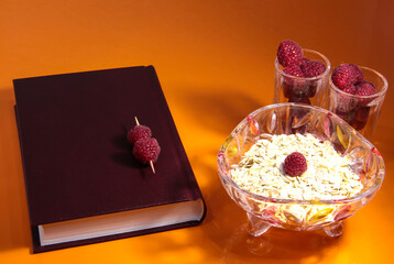 On the table is a book, berries in crystal, and oatmeal.