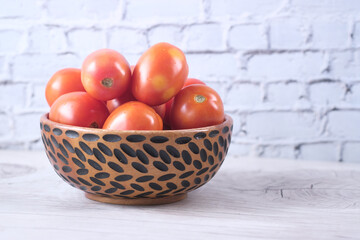close up of fresh tomato in bowl on wooden table 