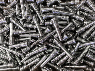 Full frame background of pile of shiny long steel parts, clean steel rods after fine cnc turning -...