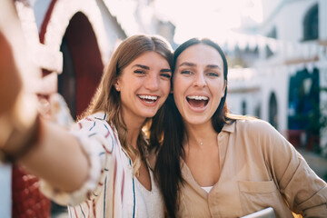 Selfie portrait of cheerful Caucasian hipster girls smiling at camera during touristic vacations for together recreation, close up of happy female friends feeling satisfied for video posing