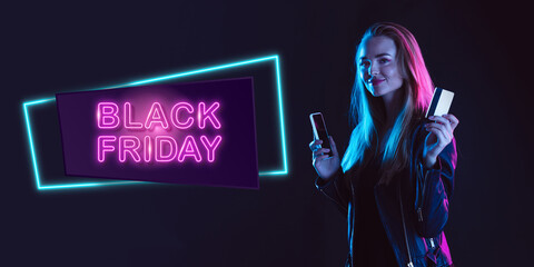 Online shopping. Portrait of young woman in neon on dark studio backgound. Human emotions, black...
