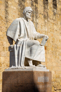 CORDOBA, SPAIN - MAY 25, 2015: The statue of medieval arabic philosopher Averroes by Pablo Yusti Conejo (1967) and the medieval walls.