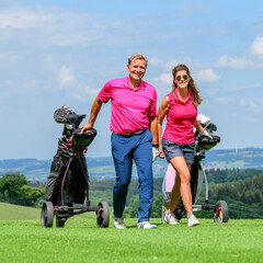 Paar gutgelaunt unterwegs auf einem Golfplatz