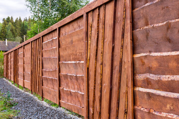 New wooden fence made of pine boards in a suburban area.