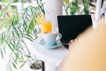 Crop freelancer with drink working in cafe