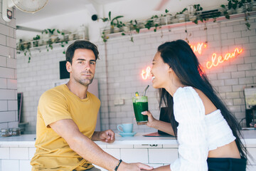 Happy multiracial couple holding hands and drinking beverages in cozy kitchen
