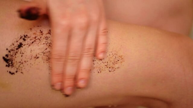 Close up woman applying coffee scrub on skin. Exfoliating legs. Anti cellulite procedure. Body care concept 