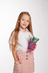 girl stands and holds a jar of felt-tip pens in her hands.