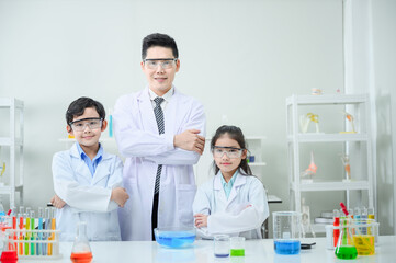 Teacher and students are looking at the camera while doing science experiments.