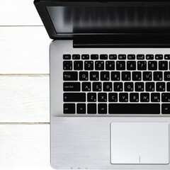 Grey laptop with black keyboard stands on white wood table